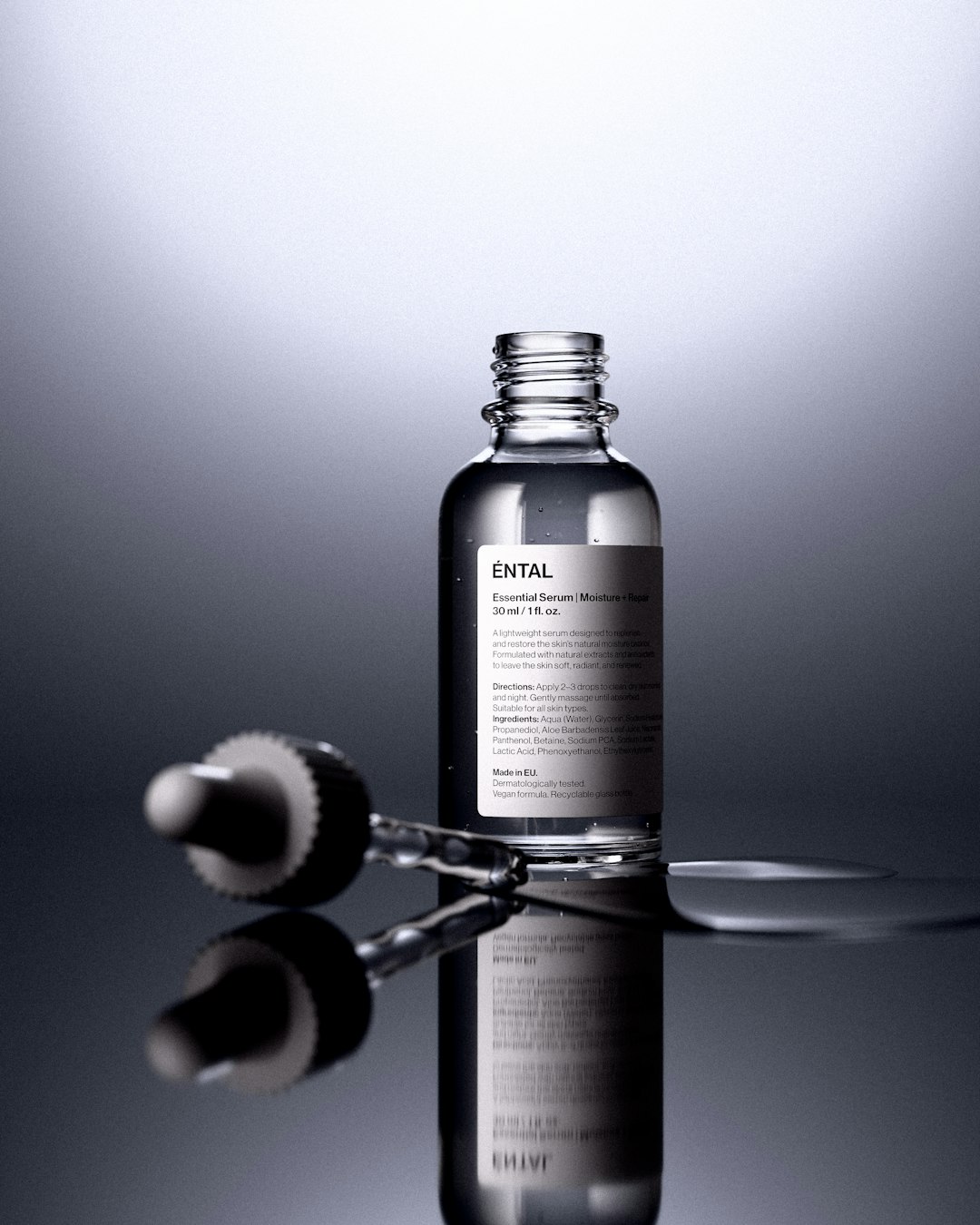 Clear serum bottle with glass dropper reflecting soft editorial studio light